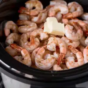 Raw shrimp, butter, lemon juice, and garlic seasoning layered in a slow cooker for scampi